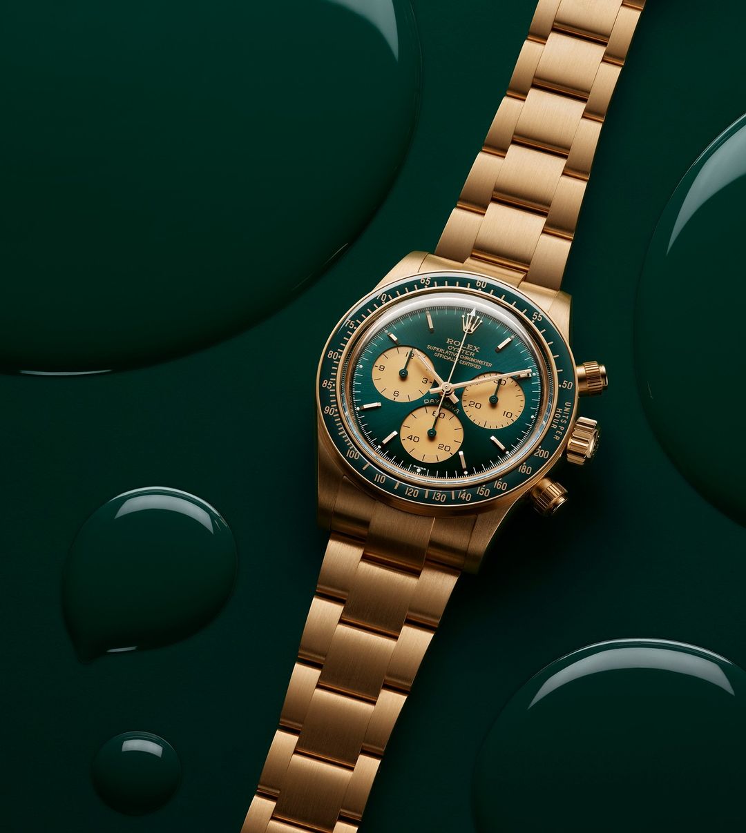 Close-up of an gold Rolex Daytona watch with a green dial on a green background with paint droplets for luxury product photography.