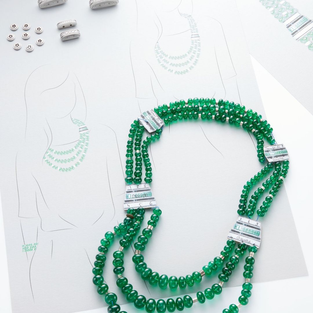 Close-up of a green beaded necklace on a white surface with design sketches of necklaces, jewelry, and embellishments in the background.