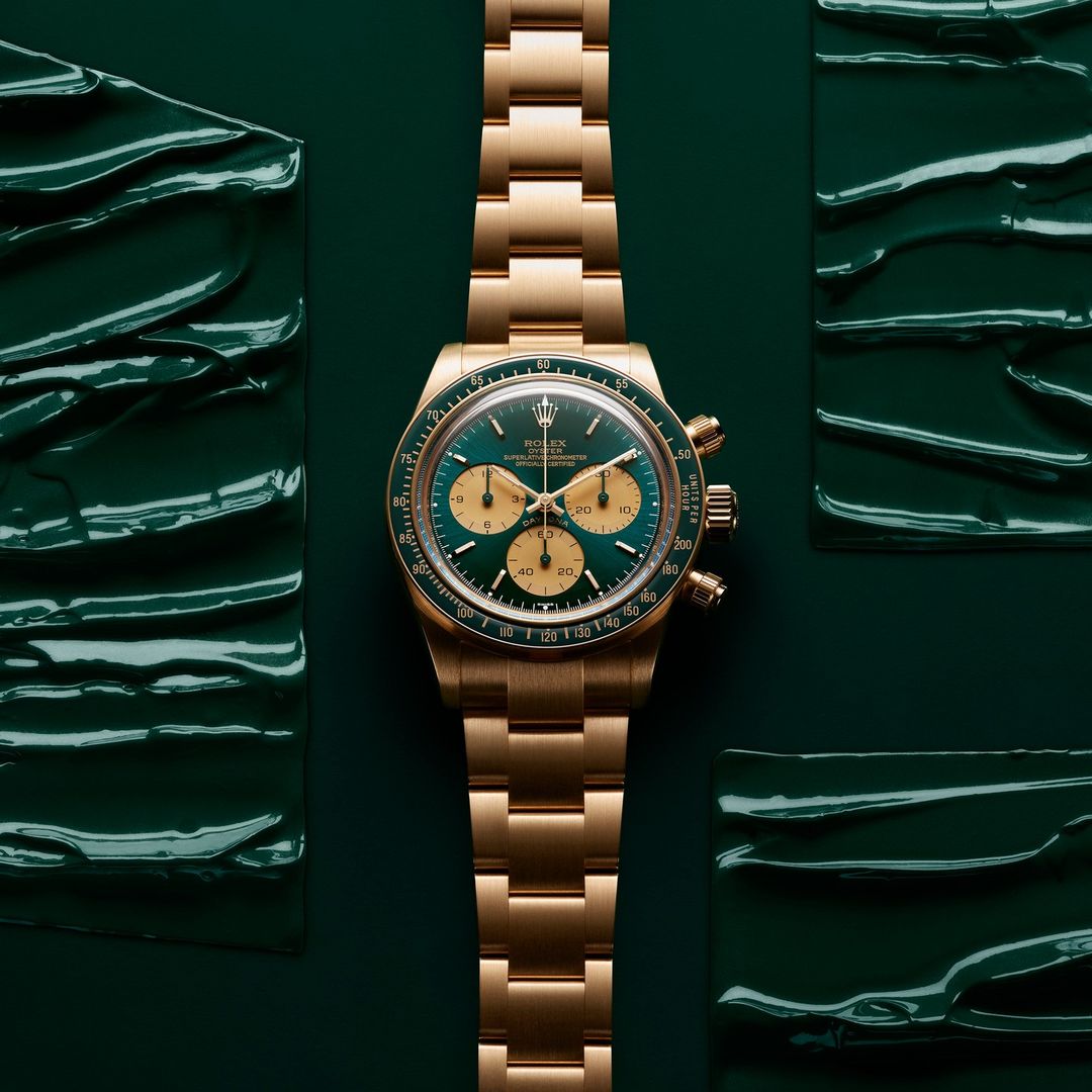 Gold Rolex Daytona watch with a green dial, showcased against a green textured backdrop, luxury timekeeping, watch photography.
