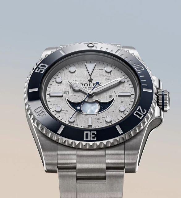 Silver Rolex Oyster Perpetual wristwatch features a meteorite dial, luminous hands, and a black ceramic bezel against a light backdrop.