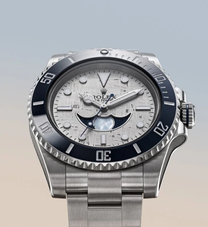 Silver Rolex Oyster Perpetual wristwatch features a meteorite dial, luminous hands, and a black ceramic bezel against a light backdrop.