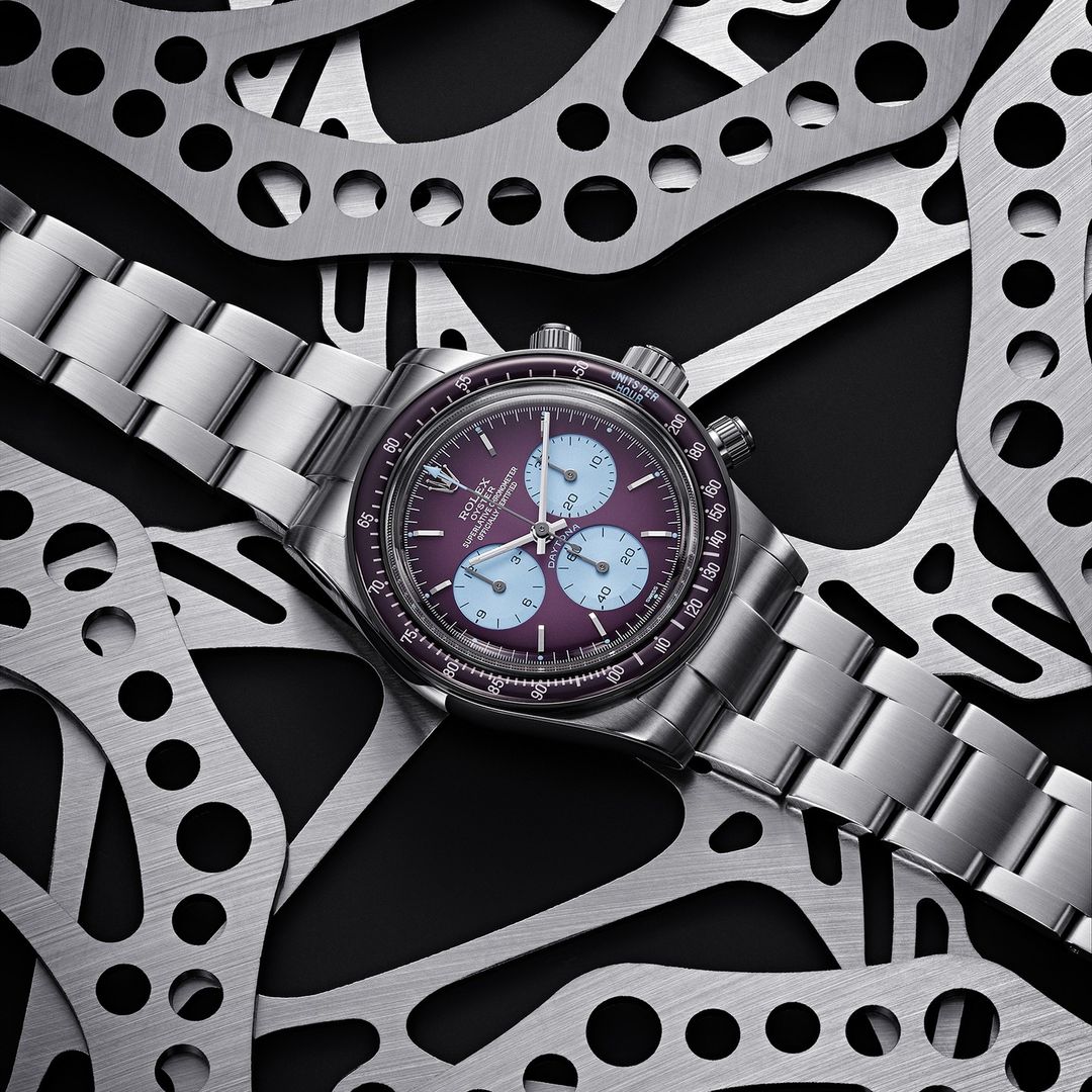 A close-up studio shot showcases a silver wristwatch with a purple face, encircled by cut metal, blending luxury with industrial textures.