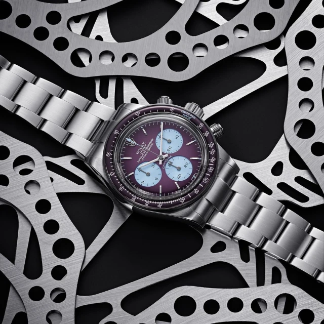 A close-up studio shot showcases a silver wristwatch with a purple face, encircled by cut metal, blending luxury with industrial textures.