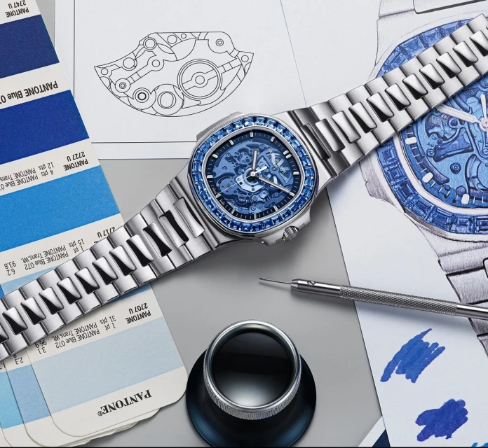 Silver luxury wristwatch with blue jeweled bezel displayed with technical blueprints and Pantone color swatches on a gray surface.
