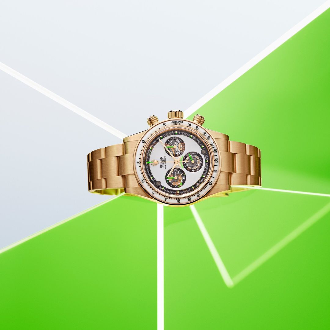 Wristwatch with a gold band on a white dial, presented against a modern background of white and green triangles and lines.