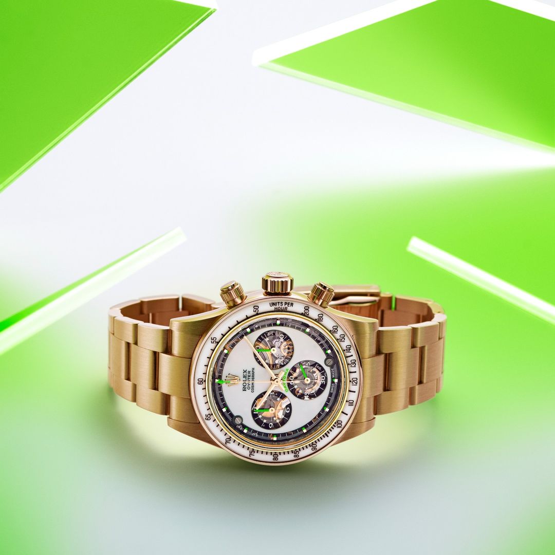 Gold Rolex Daytona watch on a light green surface with green and white abstract shapes in the background. High-end luxury watch.