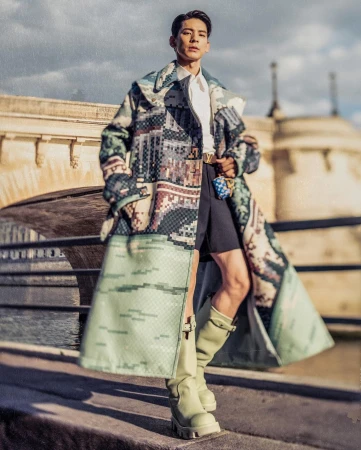Man wearing pixel-patterned long coat and tall boots posing outdoors in Paris by photographer Francois Rousseau