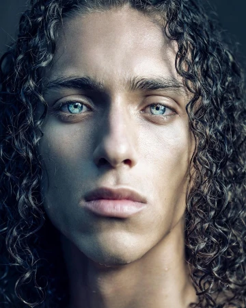 Close-up portrait of a young man with long curly dark hair and striking light blue eyes by François Rousseau