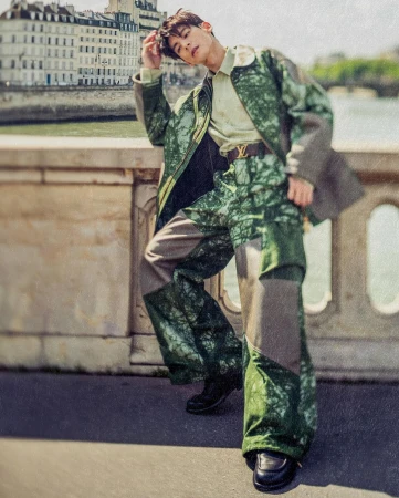 Asian male model wearing green patterned jacket and trousers posing outdoors on a bridge in Paris by François Rousseau