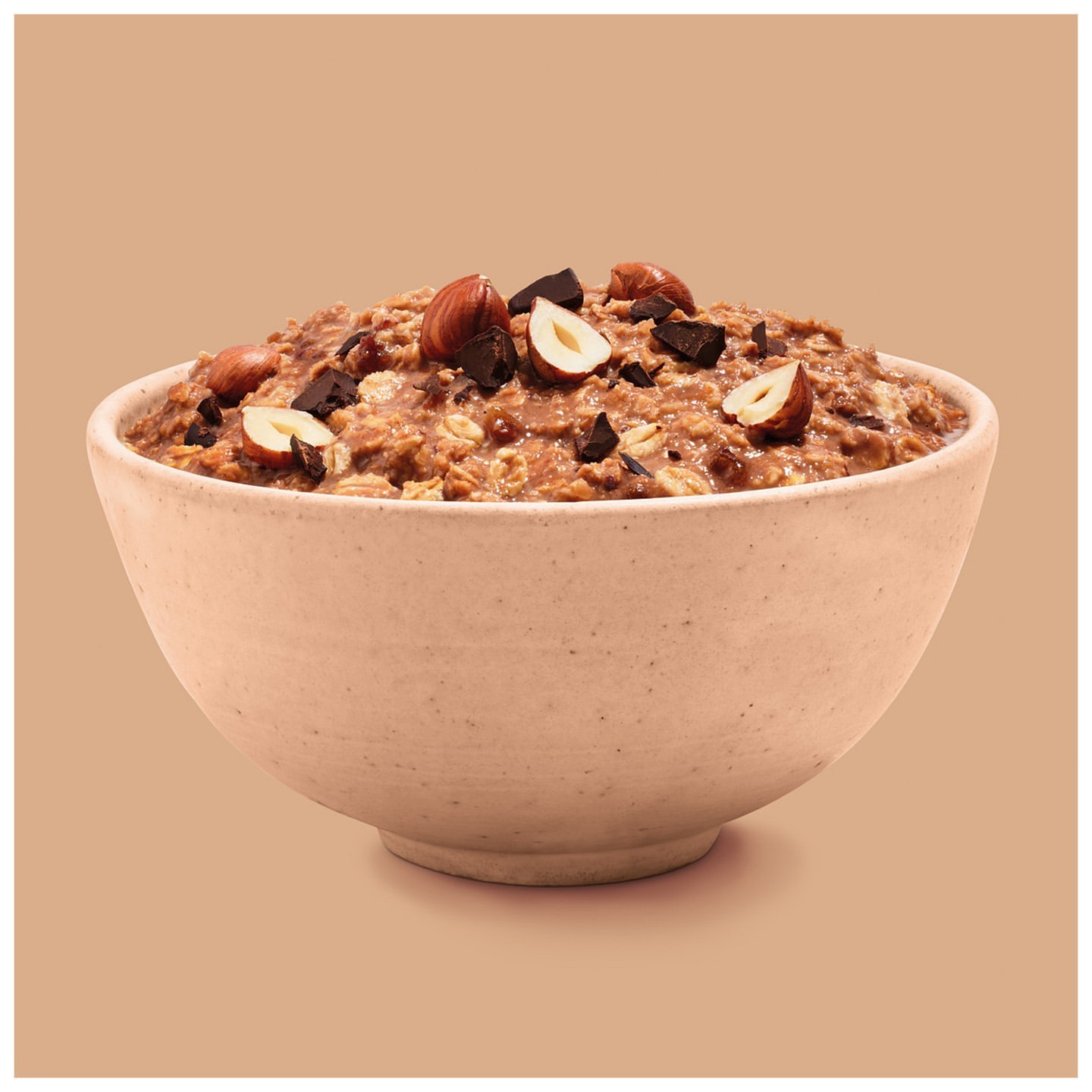 Close-up studio shot of chocolate hazelnut oatmeal in a speckled bowl, presenting a warm, inviting food photography composition.