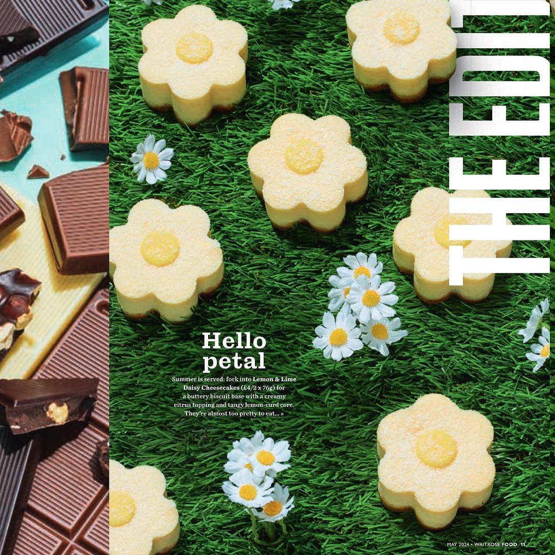 Overhead shot of flower-shaped lemon cheesecake cookies on artificial turf, presented with daisies and chocolate bars.