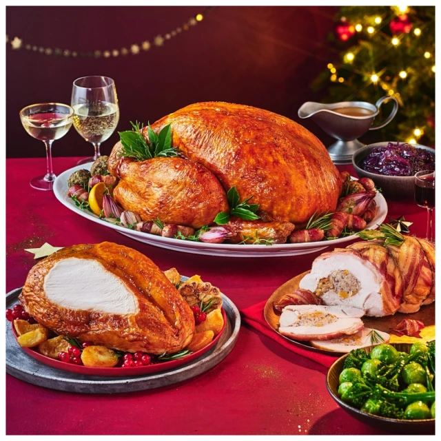 A holiday feast featuring a whole roasted turkey, sliced turkey breast, stuffing, brussel sprouts, and a variety of sides, festive Christmas setting.
