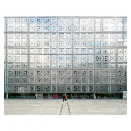Modern architecture featuring an ornate patterned facade and a large, open plaza with people walking in the urban environment.