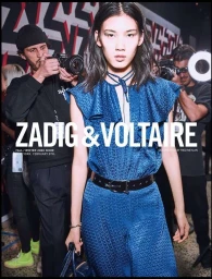 Model in blue patterned jumpsuit with a black belt photographed backstage by Fred Meylan