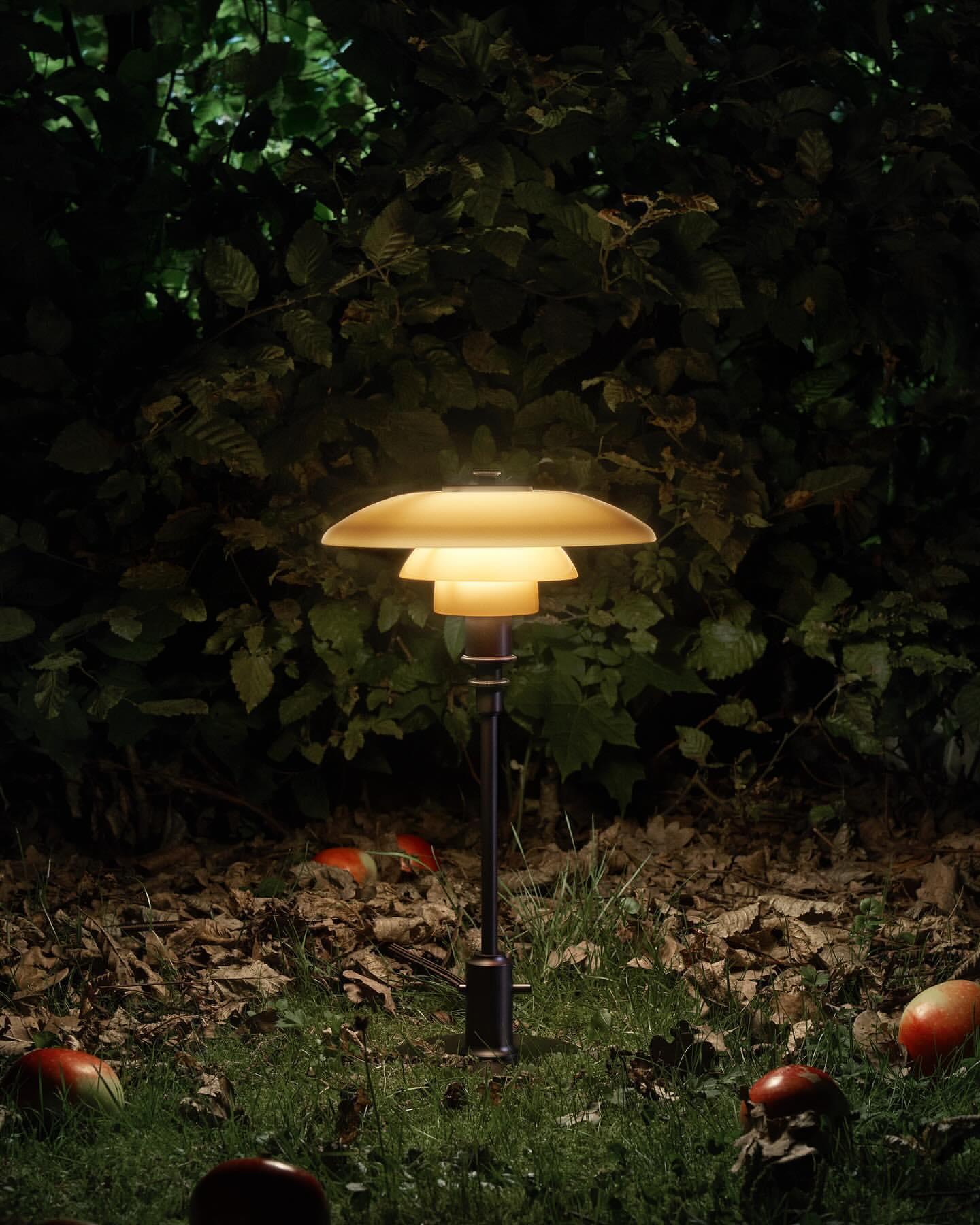 Outdoor photo of a modern layered lamp illuminating the lawn, with foliage backdrop. Warm, inviting light enhances garden ambiance.