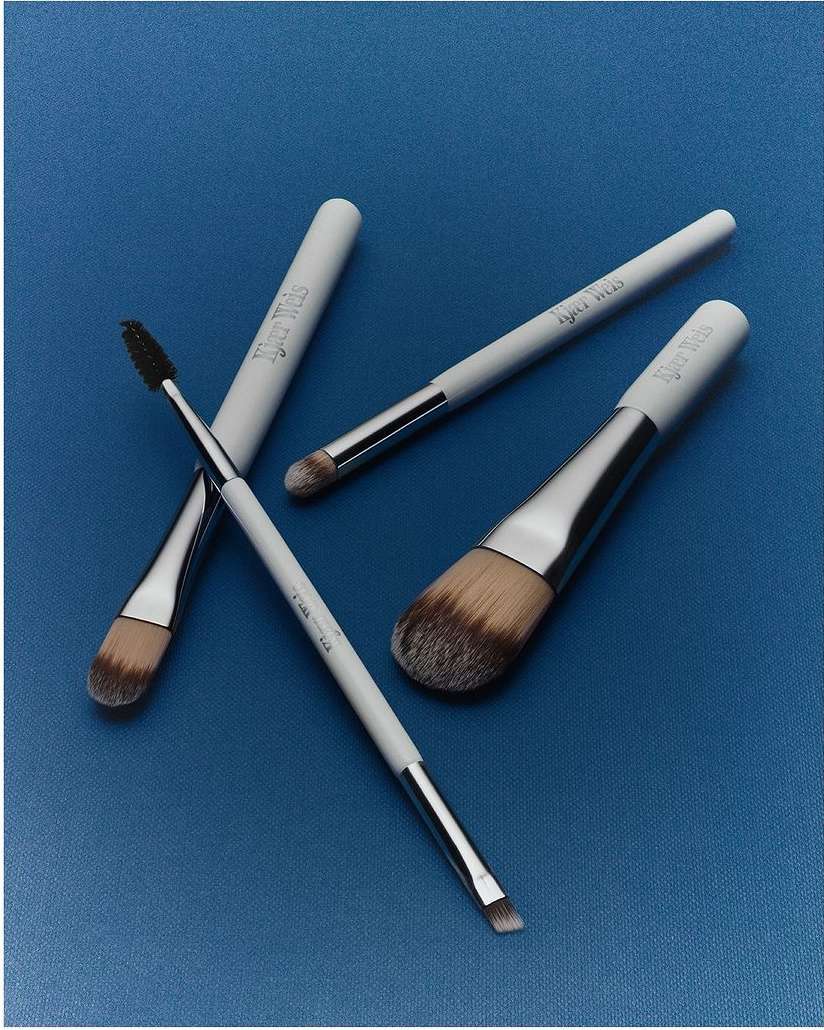 Close-up studio shot of angled makeup brushes with white handles on a blue background for beauty, cosmetics, and makeup product advertising.
