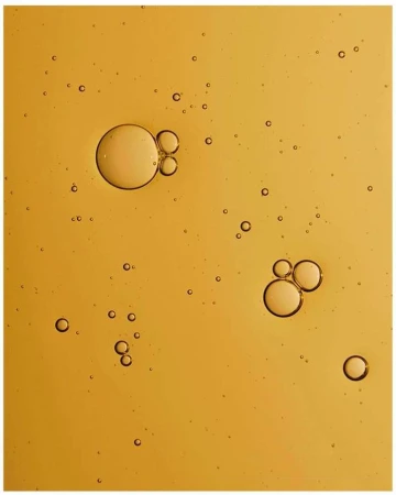 Abstract close-up of amber-colored liquid with various-sized bubbles scattered throughout, creating a textured, fluid appearance.