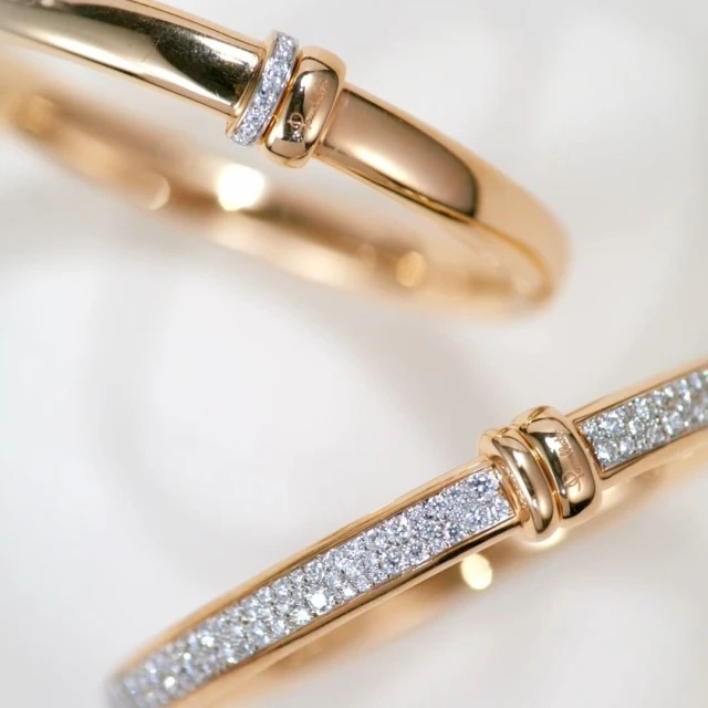 Close-up of two rose gold and diamond bangles on a white surface, highlighting fine jewelry design and luxurious craftsmanship.
