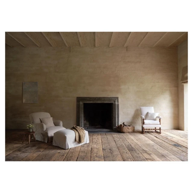 Living room interior featuring a beige fireplace, wooden floors, a recliner with an ottoman, an armchair, and natural light.