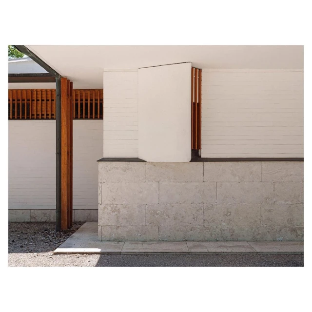 Exterior view of a modern architectural building with clean lines, featuring a stone base, white walls, and wooden slat details.