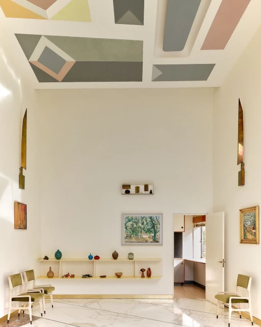Bright hallway with geometric ceiling art, marble floors, open doorway. Vases and decor on a floating shelf. Interior design.
