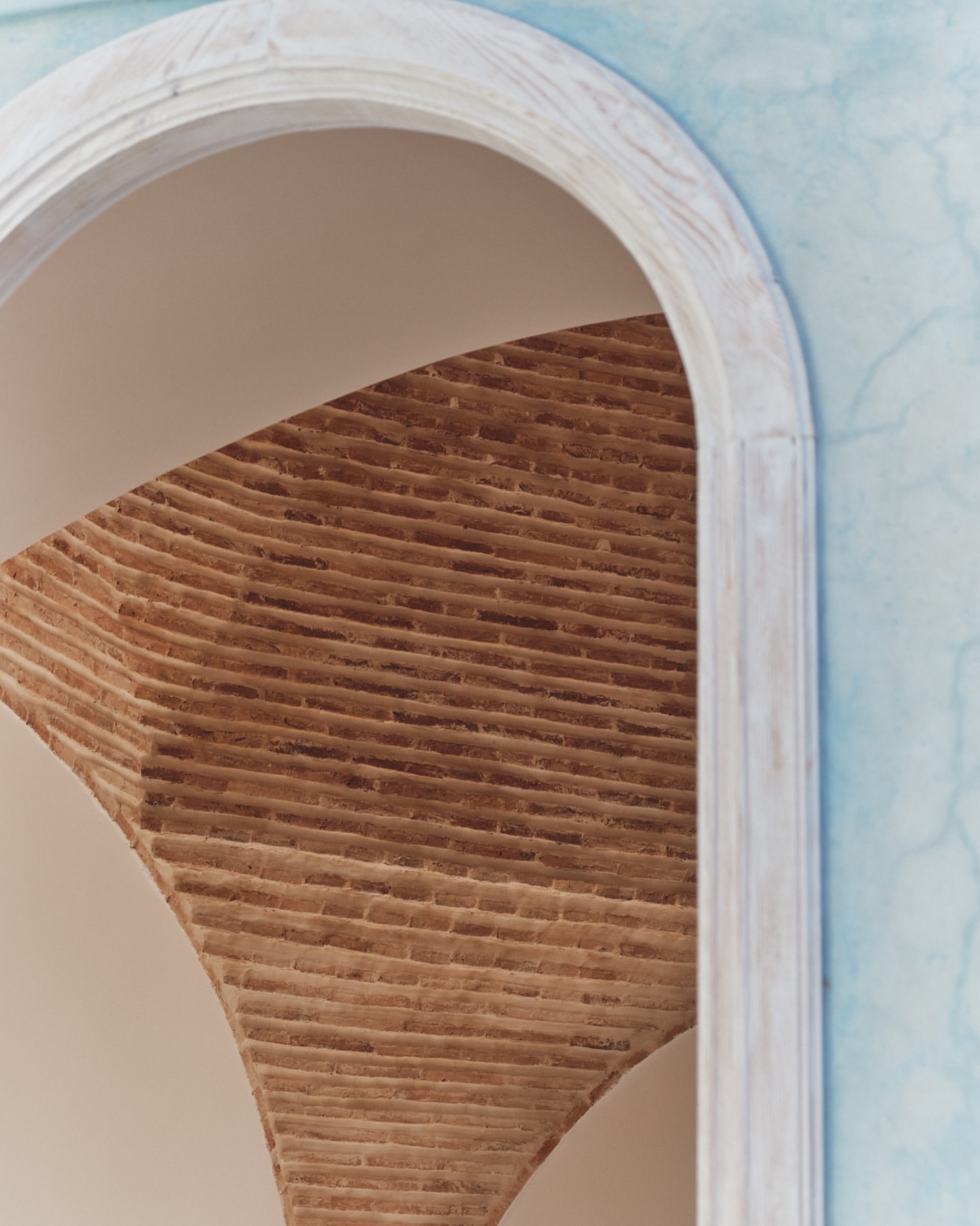 View of an arched brick ceiling under a white archway in a building, showing architecture and structural design.