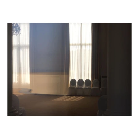 Bright, natural light illuminating a vacant room with chairs in front of a window, hinting at an event space or waiting area.