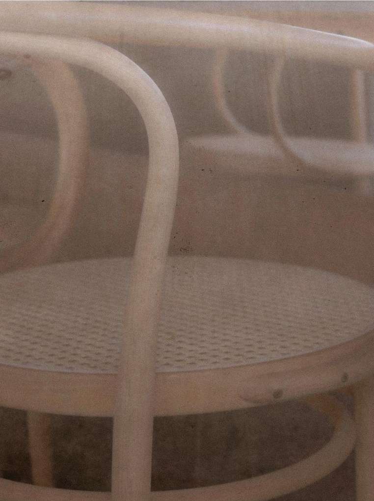 Close-up of bentwood chairs featuring rattan seating, showcasing furniture design and craftsmanship in a soft, neutral-toned composition.
