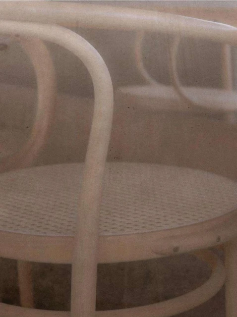 Close-up of bentwood chairs featuring rattan seating, showcasing furniture design and craftsmanship in a soft, neutral-toned composition.