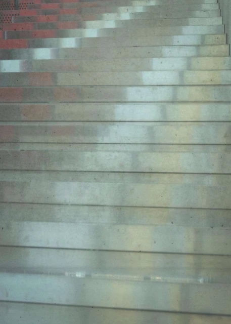 Angled view of a concrete staircase with shadows falling across the steps, creating a geometric pattern and highlighting texture.