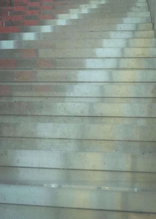 Angled view of a concrete staircase with shadows falling across the steps, creating a geometric pattern and highlighting texture.