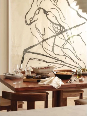 Dining room features a wooden table set with various dishes, glassware, and cutlery, with an abstract art piece in the background.