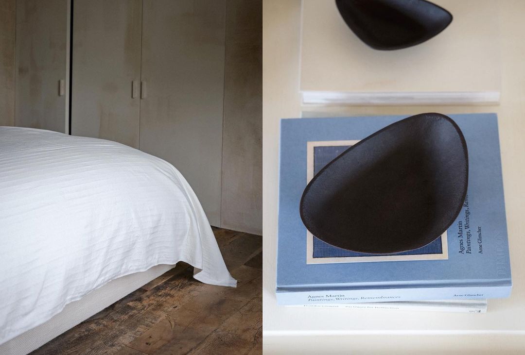 Modern interior showcasing a bedroom with a bed against a beige wall, complemented by decorative dark bowls atop stacked books.