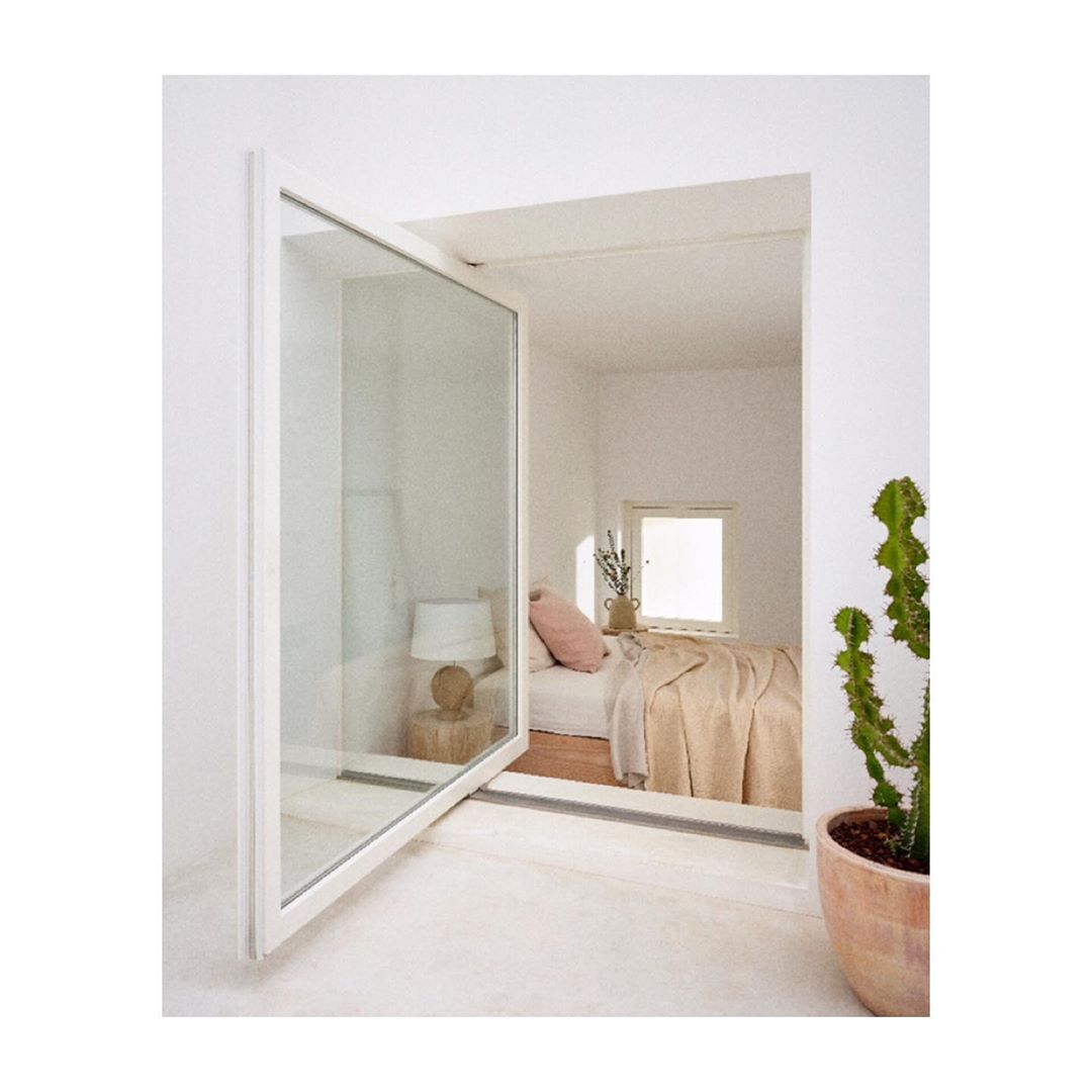 Bright, minimalist bedroom featuring an open glass window, neutral bedding, and a potted cactus in a modern interior.