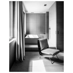 Monochrome architectural interior photography featuring a modern armchair in a minimalist bathroom by Frederik Vercruysse