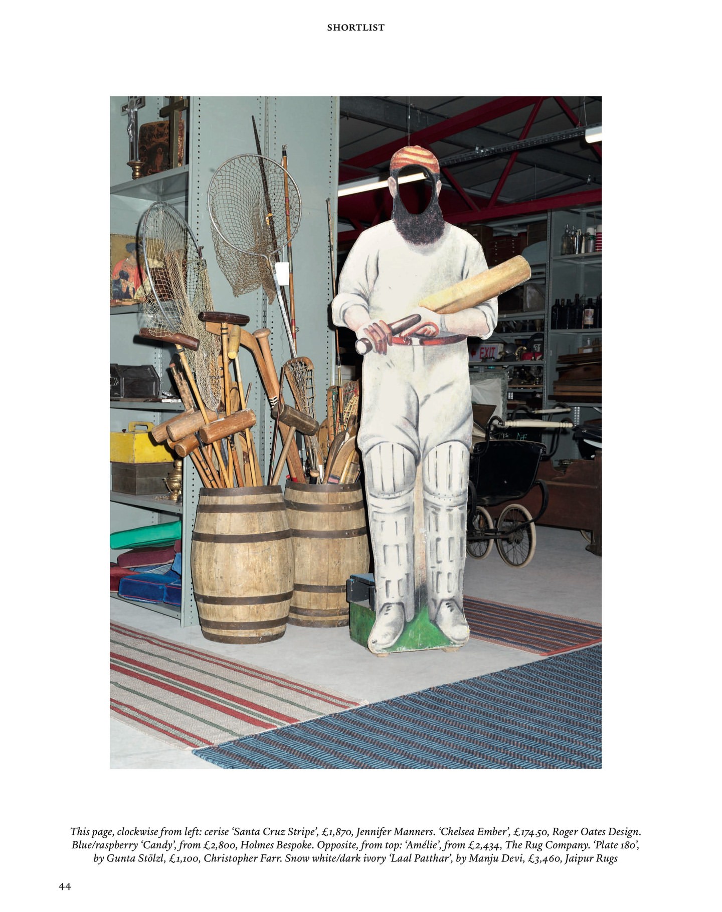 A cardboard cutout of a cricket player in full uniform stands indoors amongst barrels, netting, and other objects in a vintage setting.