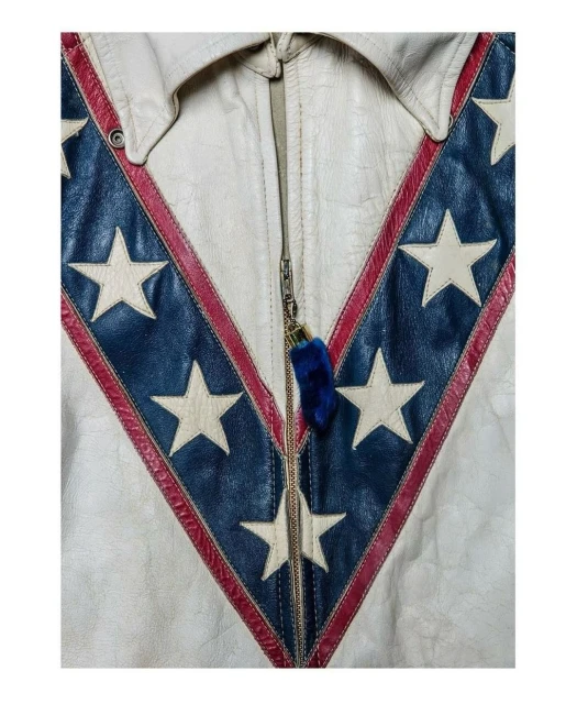 Close-up of a white leather jacket with a V-shaped blue and red pattern featuring white stars, fastened with a central zipper.