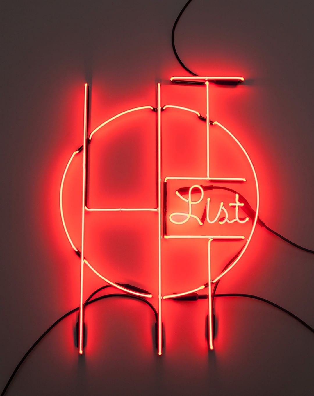 Abstract neon sign art featuring a geometric design with a circle and vertical lines, illuminated in a bright red hue on a plain background.