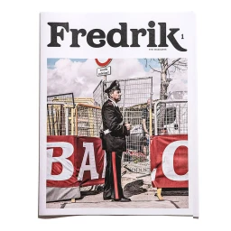 Magazine cover featuring a police officer standing near metal barricades under a cloudy sky, photographed by Fredrik Broden