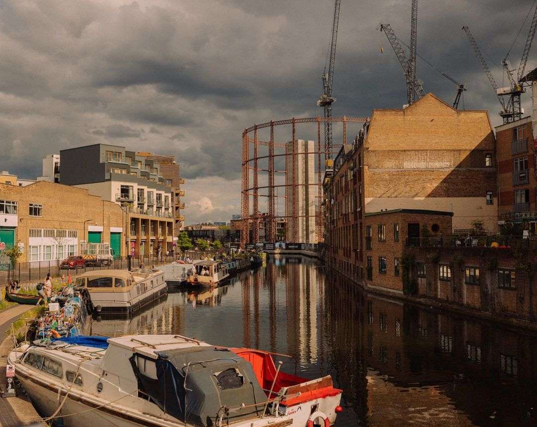 Scenic view of Regent's Canal in London, England, with colorful boats lining the waterway against a backdrop of urban architecture.