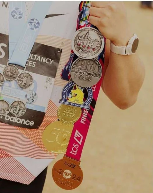 Person displaying marathon medals from races including Boston Marathon, and other races. Running achievements are on display. 