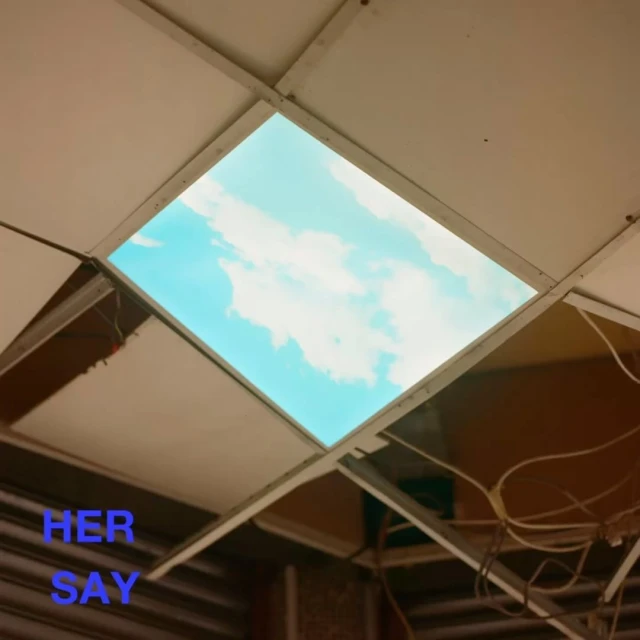 Looking up at blue sky with clouds through a rectangular ceiling panel; view of a suspended ceiling with sky view.
