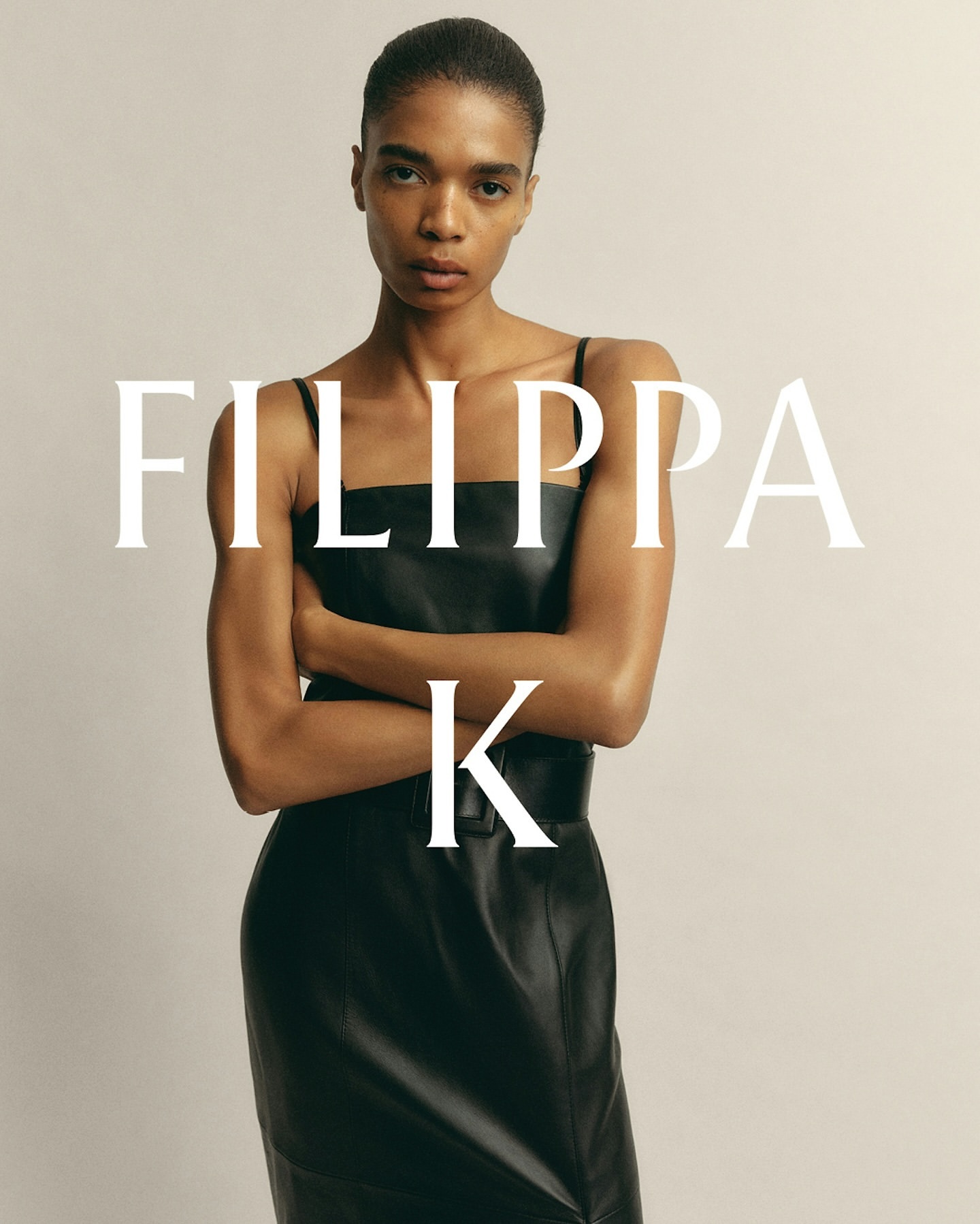 An adult fashion model poses in a black dress against a neutral backdrop, embodying a timeless style with a focus on simple elegance.