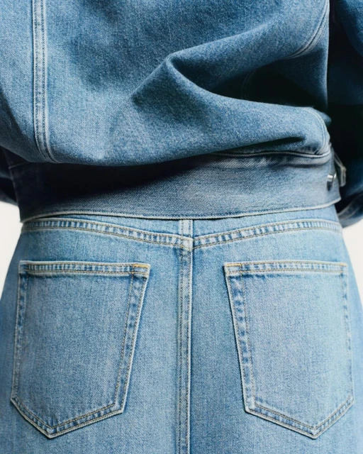 Close-up of a person wearing a light blue denim jacket and matching jeans, showcasing the back pockets and texture of the fabric.