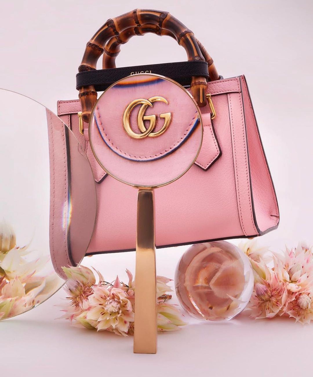 Pink Gucci handbag with bamboo handle and magnifying glass. Luxurious fashion accessory for beauty and style, studio product shot.