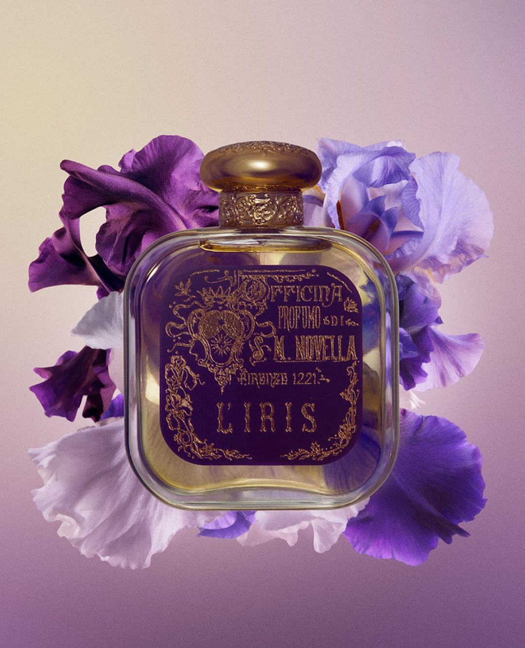 Elegant perfume bottle with a gold cap and floral label, surrounded by purple and white iris flowers on a soft gradient background.