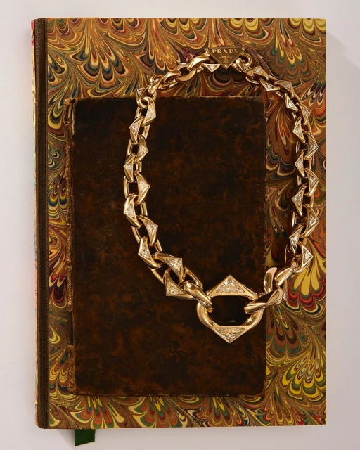 Gold-toned necklace with clear stones on a dark brown book over a marble patterned journal, captured in a vertical, close-up studio shot.