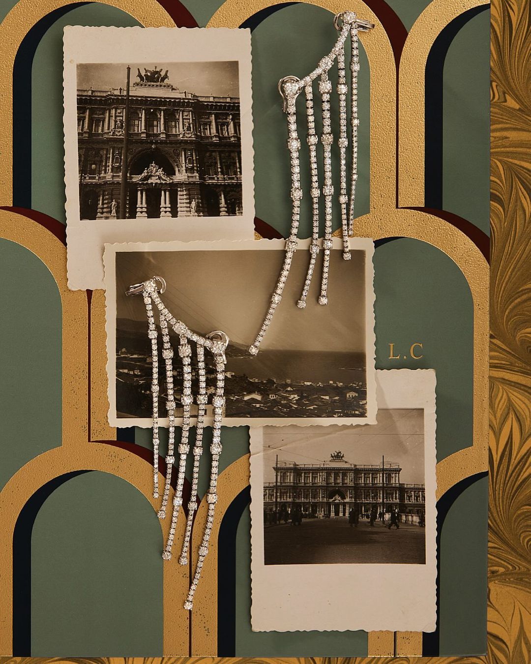 Elegant diamond fringe earrings displayed with black and white architectural photographs and ornate decorative art nouveau-inspired wallpaper.