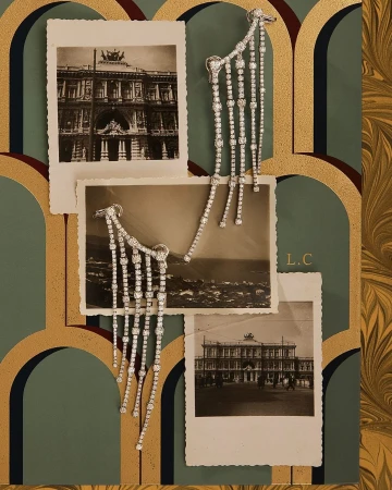 Elegant diamond fringe earrings displayed with black and white architectural photographs and ornate decorative art nouveau-inspired wallpaper.