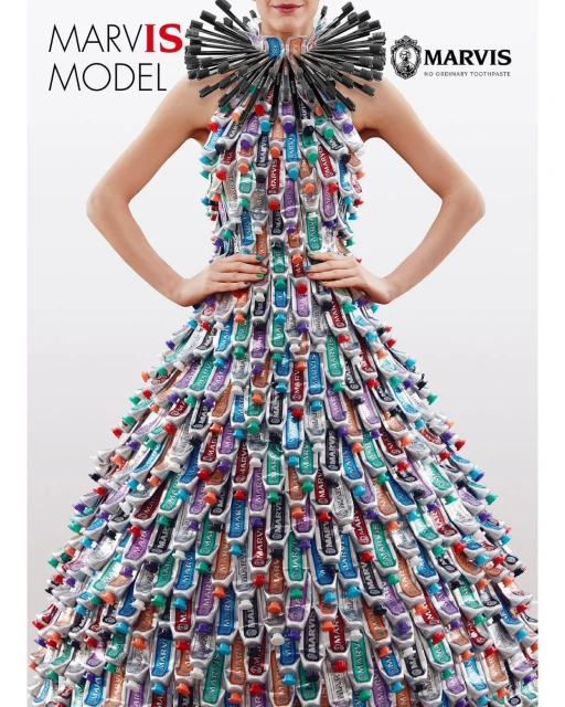 Model wears a dress and collar constructed from Marvis toothpaste tubes in a fashion editorial against a clean white backdrop.